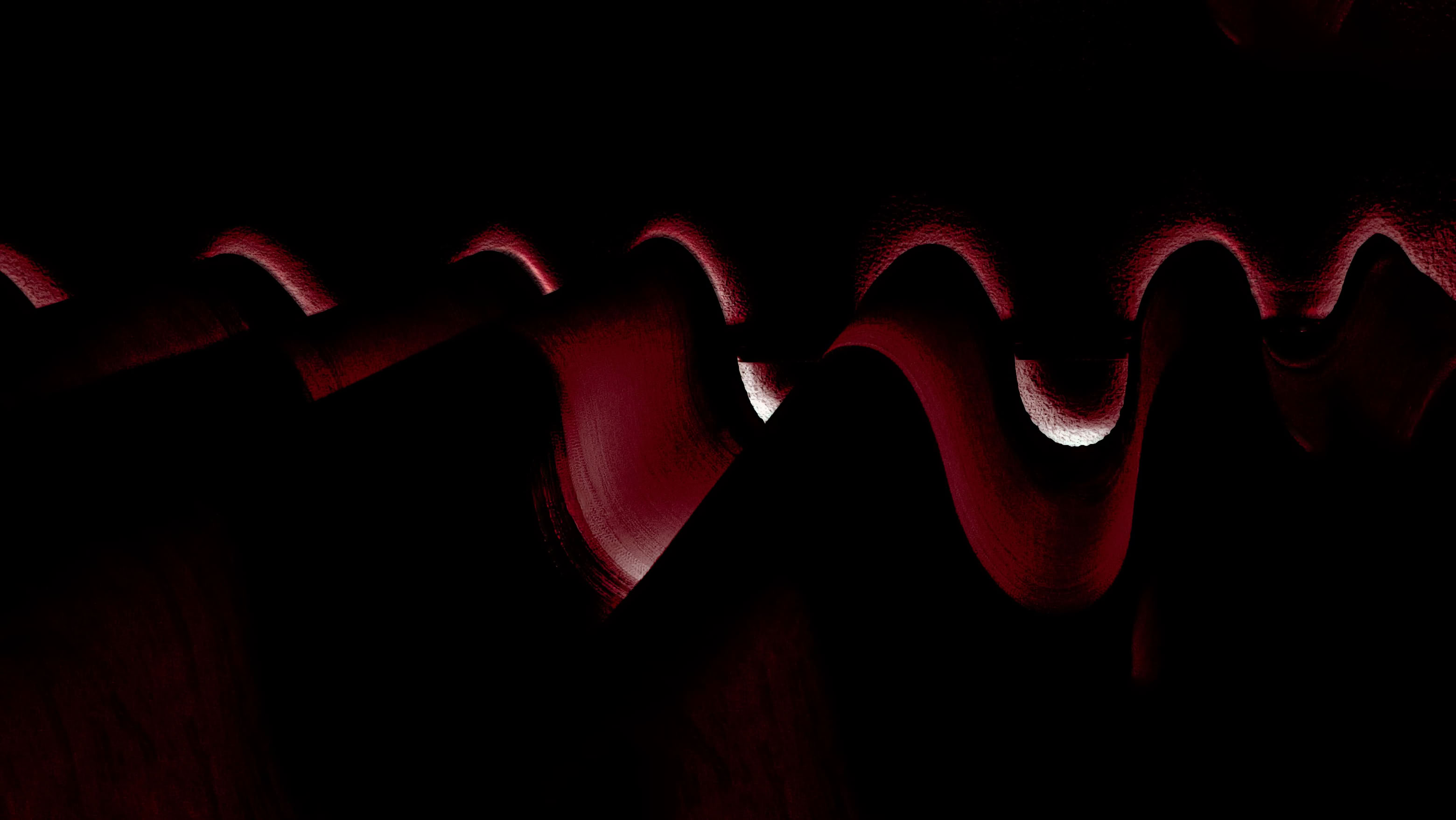 Abstract image with dark red and black wavy patterns and shadows.