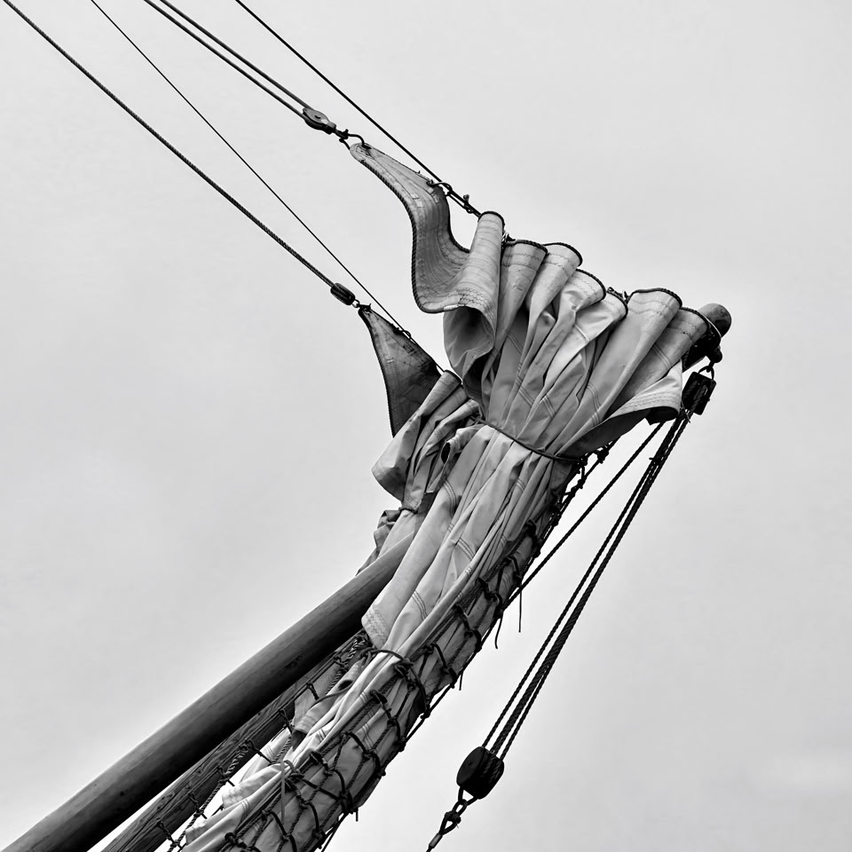 Close-up of a ship's bow with ropes and sails against a cloudy sky.nHarlingen, Netherlands