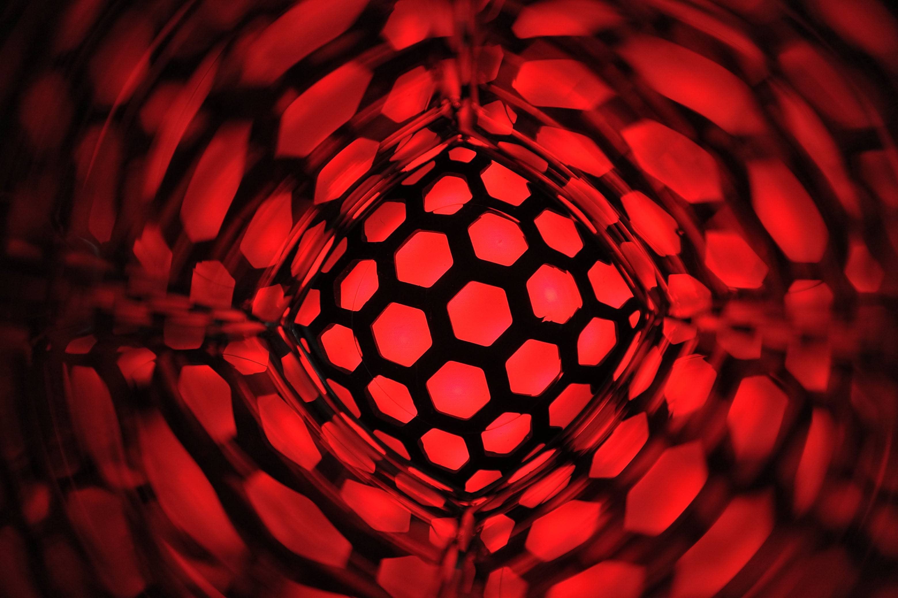 Red and black hexagonal pattern with a glowing effect, creating a tunnel-like appearance.