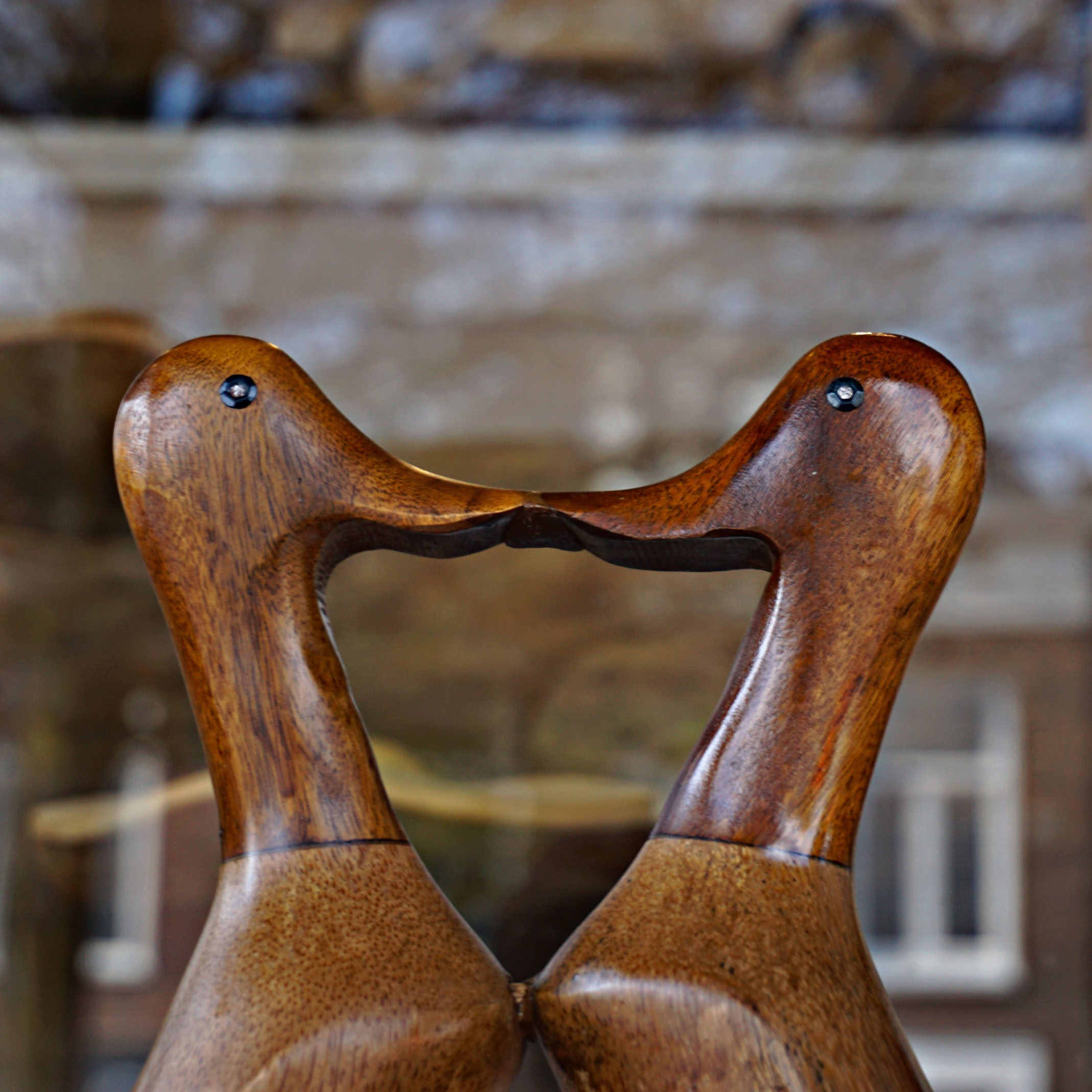 Two wooden duck sculptures facing each other with their beaks touching.