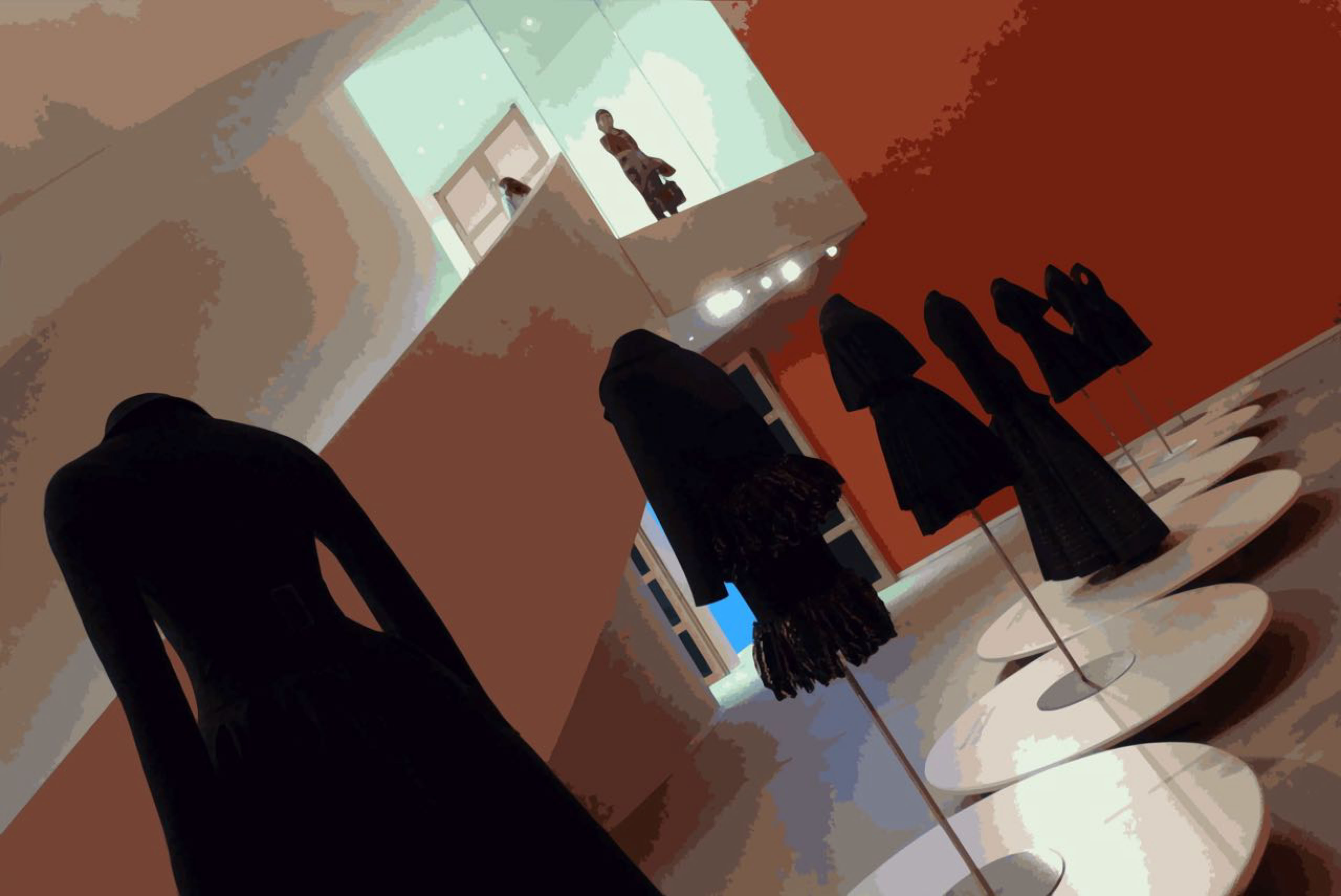 Mannequins displaying black clothing on circular platforms in a modern gallery space with a red wall and upper level.