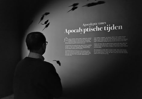 A person standing in front of a wall with text and shadowy mouse figures.