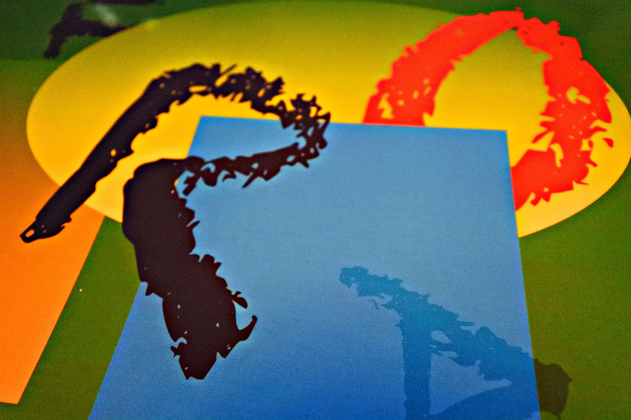 Abstract shapes and colors including a blue rectangle, a yellow circle, and a red arc on a green background.
